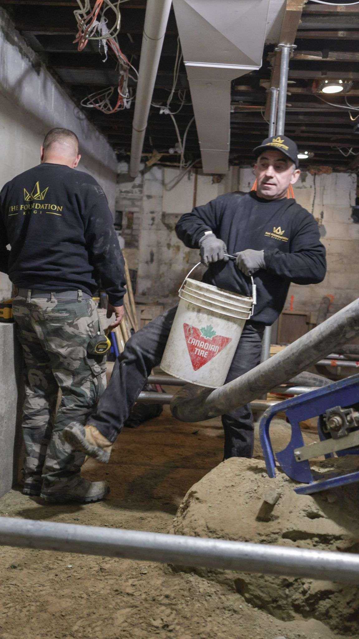 Two Foundation Kings crew members in branded sweaters underpinning a Moore Park basement in Toronto