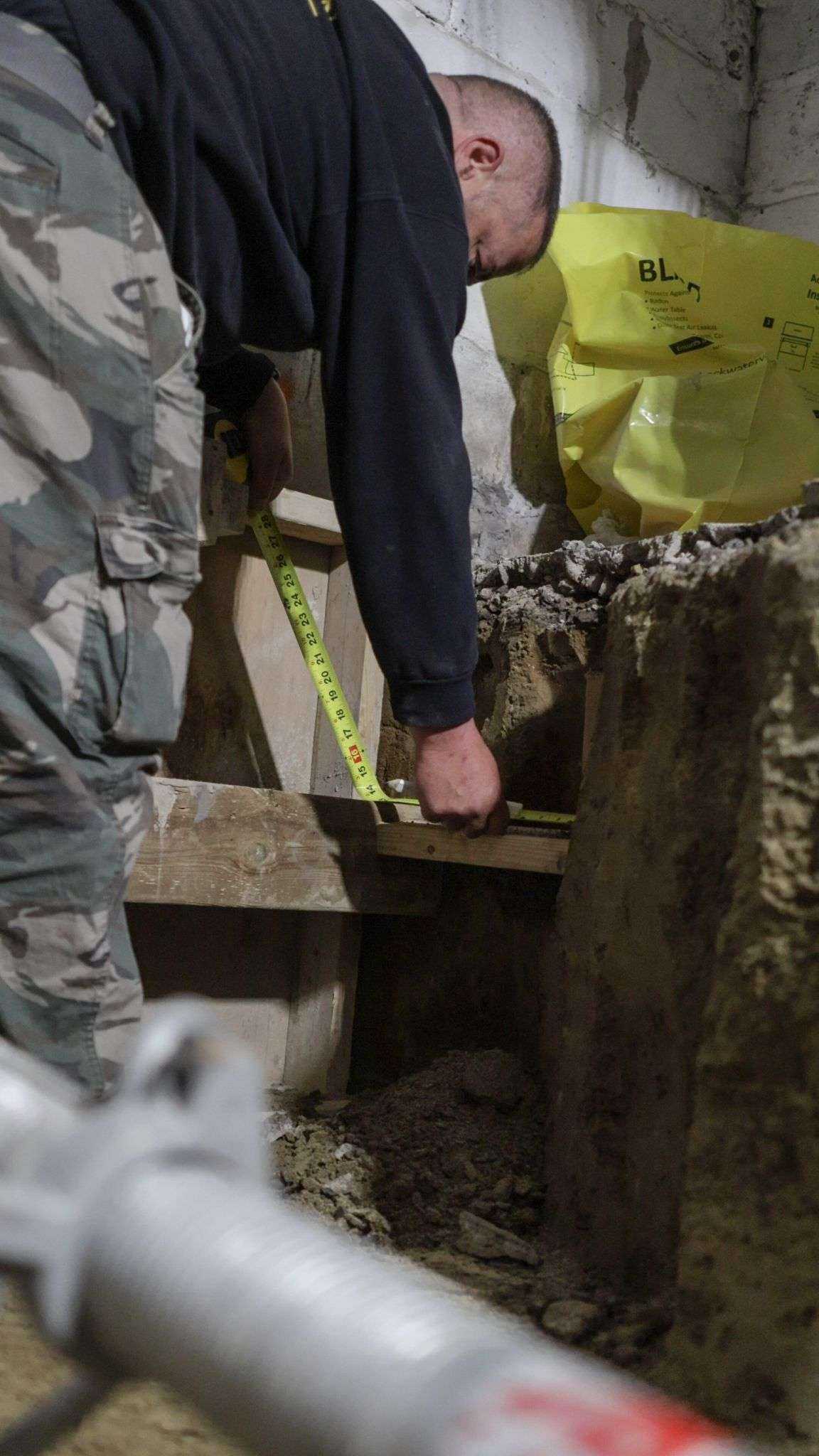 Measuring the depth of an underpinning pin excavation with a tape
