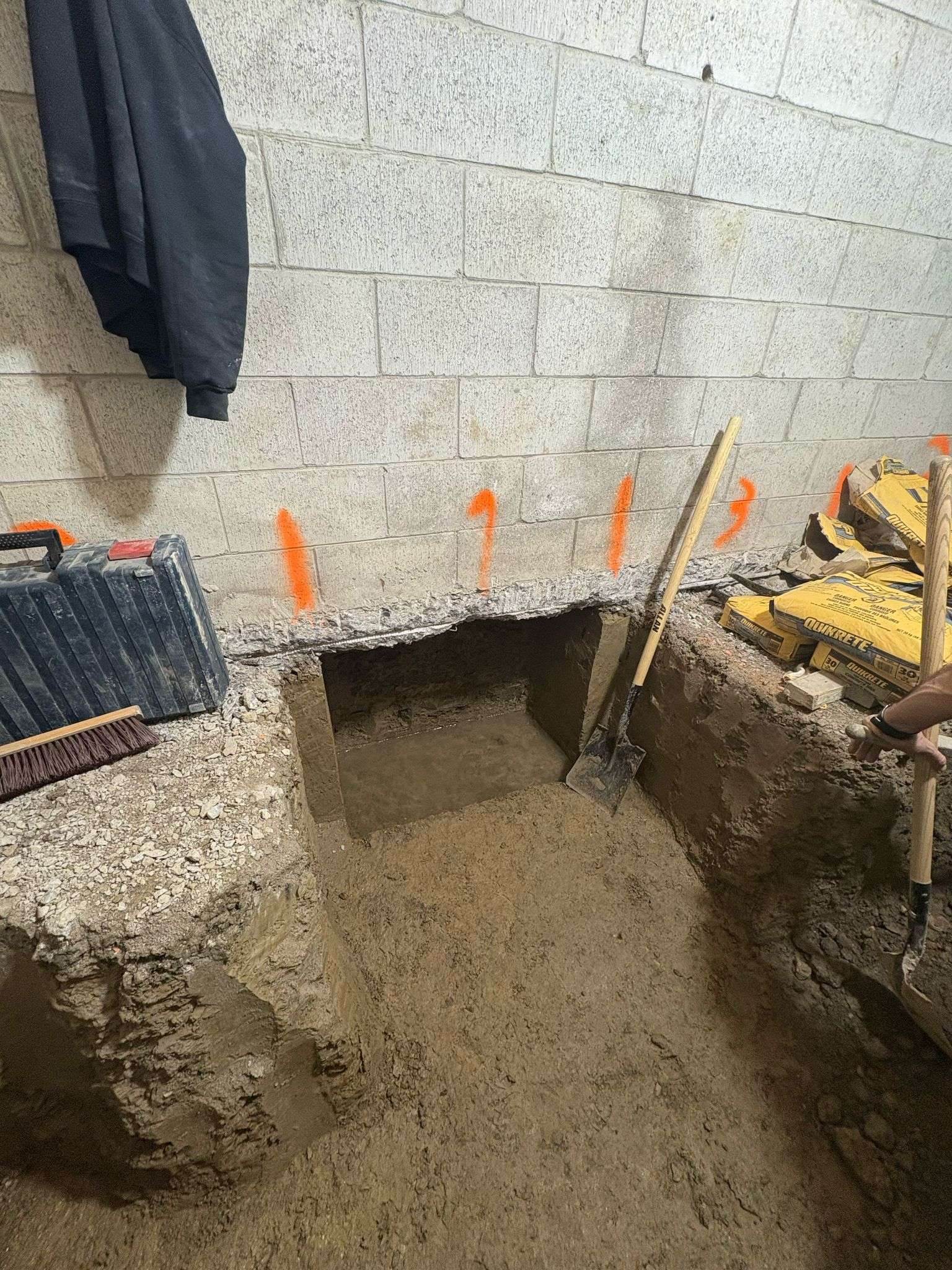 Underpinning pins numbered in orange paint along a basement wall to show the excavation sequence