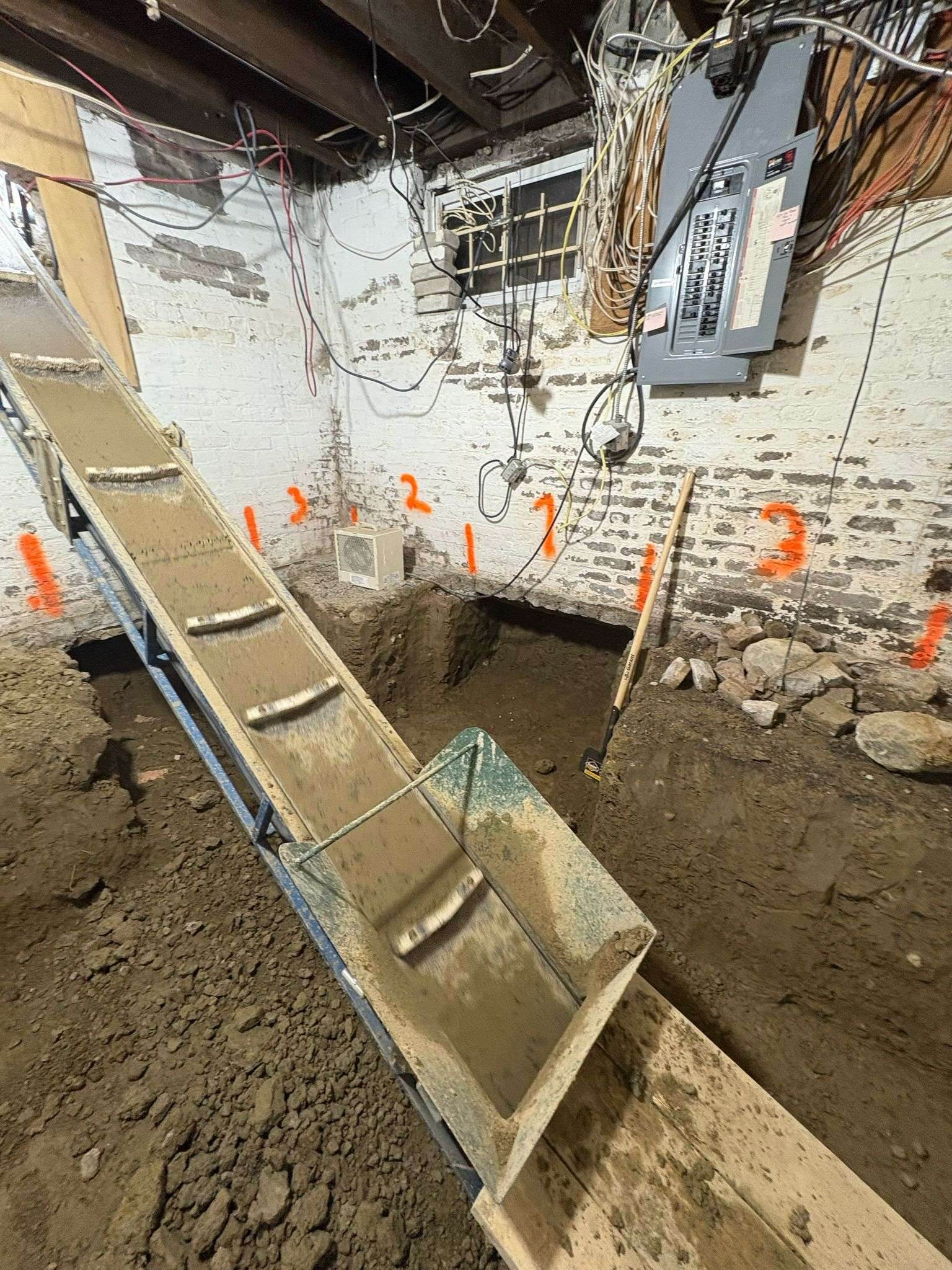 Soil conveyor carrying excavated earth out of a basement window