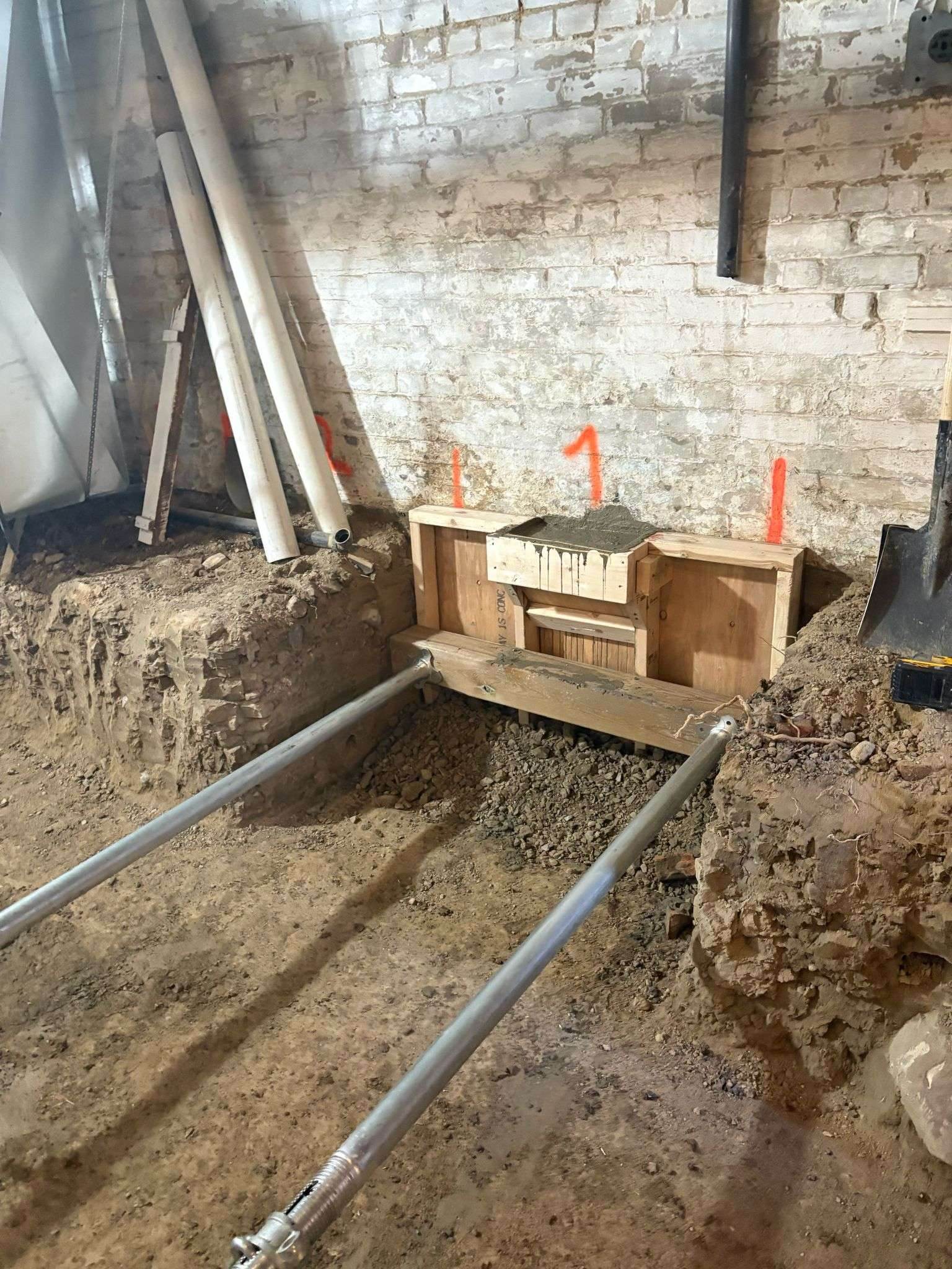 Underpinning pin forms and shoring along a brick foundation wall